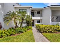 Inviting condo exterior featuring lush landscaping, a private balcony, and a welcoming walkway to the front door at 1100 Capri Isles Blvd # 215, Venice, FL 34292