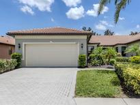 Charming single-story home featuring a tile roof, brick driveway, and well-manicured landscaping at 11192 Campazzo Dr, Venice, FL 34292