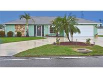 Charming single-story home featuring a manicured lawn, mature palm trees, and an attached two-car garage at 1198 Jamaica Rd, Venice, FL 34293