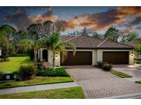 Inviting home featuring a brick driveway, lush landscaping, and a tile roof at 12187 Amica Loop, Venice, FL 34293