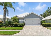 Charming single-story home with a two-car garage, paver driveway and lush landscaping at 1234 Harbor Town Way, Venice, FL 34292