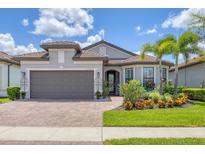 Beautiful single-story home with lush landscaping, a brick driveway, and a two-car garage at 13092 Rinella St, Venice, FL 34293