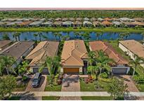 Beautiful aerial view of homes with tile roofs, manicured landscaping, and a serene lake in the community at 13841 Campoleone St, Venice, FL 34293