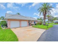 Charming single-story home featuring a well-manicured lawn, tiled roof, palm trees, and a two-car garage at 16 Oakwood N Dr # 16, Englewood, FL 34223