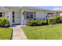 Charming single-story home featuring a well-maintained lawn, walkway and quaint front door at 168 The Corso # 168, Venice, FL 34285