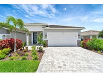 Charming single-story home with a two-car garage, beautiful landscaping, and a paver driveway at 17873 Grand Prosperity Dr, Venice, FL 34293