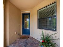 Inviting covered entryway with a decorative blue front door, brick pavers, and a welcome mat at 19269 Serafina St, Venice, FL 34293