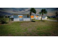 Charming single-story home with two palm trees, a well maintained lawn, and a white exterior at 20430 Edgewater Dr, Port Charlotte, FL 33952