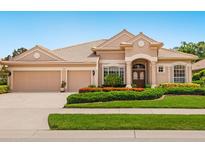 Charming single-story home with a tile roof, three-car garage, and beautifully landscaped front yard with flowers at 355 Swallow Cir, Venice, FL 34285