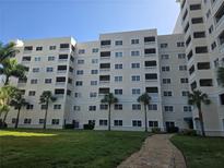Multi-story condo complex with multiple units, balconies, and palm trees, set in a grassy lawn at 3730 Cadbury Cir # 703, Venice, FL 34293