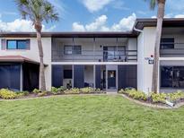 Condo exterior featuring a manicured lawn, palm trees, and a screened-in porch, offering a blend of indoor/outdoor living at 401 Airport E Ave # 304, Venice, FL 34285