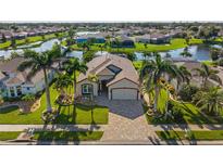 Beautiful waterfront home with lush landscaping, brick driveway and palm trees, creating a tropical paradise at 4260 Wordsworth Way, Venice, FL 34293
