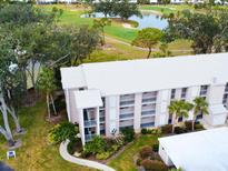 An aerial view of a condo building with a golf course and water feature in the background at 437 Cerromar Ln # 513, Venice, FL 34293