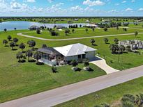 Expansive aerial view of a home with lush green lawn, screened in pool, lake view, and long driveway at 48 Lark Dr, Placida, FL 33946