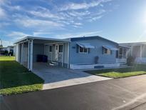 Charming single-story home with light blue siding, awnings, covered carport, and well-maintained landscaping at 529 Cervina S Dr, Venice, FL 34285