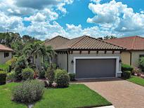 Charming single-story home with a tile roof, manicured landscaping, and a paver driveway leading to a two-car garage at 5832 Semolino St, Nokomis, FL 34275
