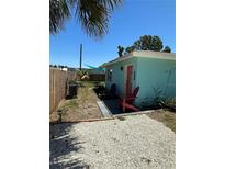 Charming exterior view featuring a teal home with coral colored door and Adirondack chairs at 700 Forest St, Nokomis, FL 34275