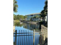 Scenic view of a well-maintained apartment complex overlooking a pond with palm trees at 700 Gardens Edge Dr # 722, Venice, FL 34285