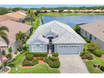 Charming single-story home features well-manicured landscaping and a paver driveway, nestled by a serene lake at 809 Derbyshire Dr, Venice, FL 34285