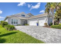 Stunning single-story home featuring a meticulously maintained lawn, paver driveway, and three-car garage at 8245 Grande Shores Dr, Sarasota, FL 34240