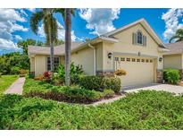 Charming home featuring a well-manicured lawn, lush landscaping, and a two-car garage at 9361 Carnaby Dr, Venice, FL 34293