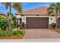 Beautiful home exterior showing lush landscaping, a brick driveway and a two-car garage at 121 Colebrook Ct, Venice, FL 34292