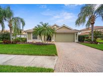 Charming single-story home featuring a well-manicured lawn, mature palm trees, and a paver driveway at 2396 Caraway Dr, Venice, FL 34292