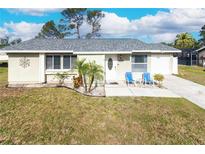 Charming single-story home featuring a well-maintained lawn and welcoming entrance with seating at 7585 Kavanda St, North Port, FL 34287