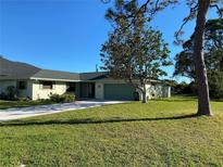 Charming single-story home with a green lawn, mature trees, and a driveway leading to an attached garage at 4250 Shamrock Dr, Venice, FL 34293