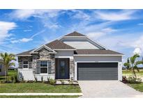 Modern one-story home with gray garage door and stone accents at 25491 Calusa Dr, Punta Gorda, FL 33955