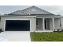 New single-story home with gray siding, a black garage door, and a landscaped lawn at 25372 Alicante Dr, Punta Gorda, FL 33955