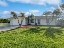 White house with a green lawn and palm trees in the front at 865 Everest Rd, Venice, FL 34293
