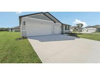 Two-car garage, gray siding, and landscaping at 14074 Ginnie Springs Way, Parrish, FL 34219