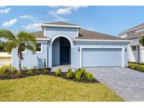 Charming single-story home with a blue exterior, arched entry, and well-manicured landscaping at 9593 Vibrant Lane, Venice, FL 34292