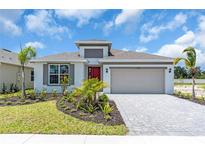 Charming single-Gathering home with a red door, landscaped yard, and a two-car garage at 9577 Vibrant Lane, Venice, FL 34292