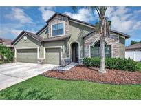 Two-story house with three-car garage, stone accents and palm trees at 6722 Wild Elm Ct, Wesley Chapel, FL 33545
