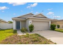 Tan one-story house with a two-car garage and grey front door at 12120 Barnsley Reserve Pl, Gibsonton, FL 33534