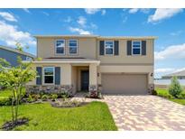 Two-story house with a neutral color scheme, landscaping, and a brick paver driveway at 9034 Sandy Bluffs Cir, Parrish, FL 34219