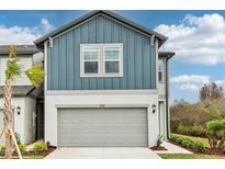 Two-story townhome boasts a modern exterior with gray siding and a gray garage door at 7628 Intrepid Rd, Wesley Chapel, FL 33545