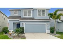 Two-story home with light blue exterior, two-car garage, and landscaping at 11334 Hudson Hills Ln, Riverview, FL 33579