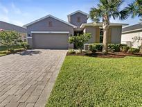 Two-story house with gray siding, paver driveway, and landscaped yard at 12545 Ryegrass Loop, Parrish, FL 34219