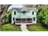 Two-story light teal home with a wrap around porch at 210 15Th E St, Bradenton, FL 34208