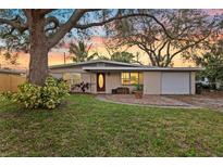 Charming single-story home featuring mature trees, a well-manicured lawn, and attached garage at 1023 Madison St, Largo, FL 33770