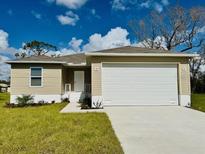 A charming single Gathering home boasts a large two car garage and manicured lawn at 17384 Robinson Ave, Port Charlotte, FL 33948