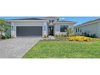 Charming single-story home boasts a meticulously landscaped front yard and attached two-car garage at 4990 Fairhope Cir, Lakewood Ranch, FL 34211