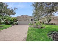 Exterior of a tan house with a brick driveway and landscaping at 7423 Wexford Ct, Lakewood Ranch, FL 34202