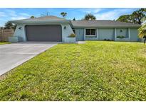 Newly renovated home with gray garage door and green lawn at 3451 Sage St, Port Charlotte, FL 33948