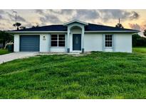 House exterior featuring a gray garage door and lush green lawn at 4469 Cunningham St, Port Charlotte, FL 33948