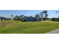 Charming single-story blue home with a well-maintained lawn and palm trees at 3420 Ash St, Punta Gorda, FL 33950