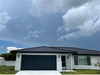 White brick home with a black metal roof and garage at 1359 Cambridge Dr, Venice, FL 34293